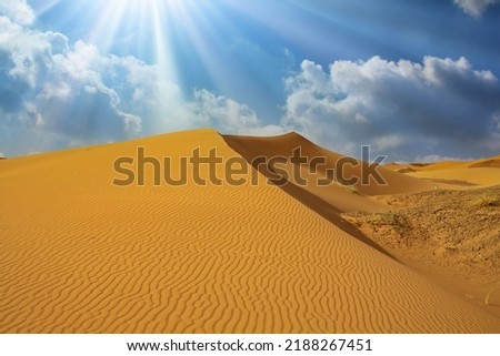 Beautiful african desert landscape, triangle shape yellow sand dune, dramatic sky clouds, sun rays backlight - Morocco, Erg Chebbi, North Africa Royalty-Free Stock Photo #2188267451