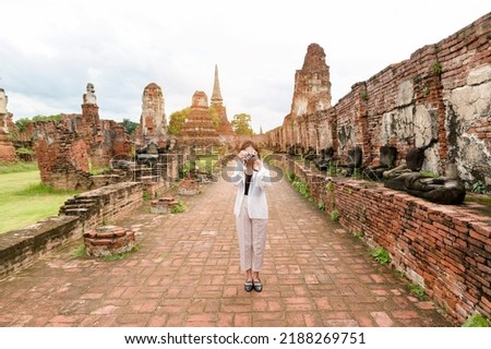 young beautiful woman traveling and taking photo at thai historical Park, Holidays and cultural tourism concept.