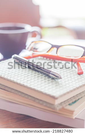 Pen and eyeglasses on three notebooks in coffee shop, stock photo
