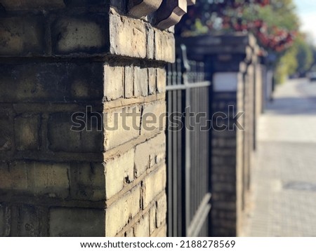 Vintage brick fence with house number close-up. Old street, landscaping and home life concept