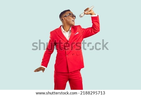 African American man singing in microphone isolated on light background. Stylish young ethnic singer taking part in karaoke party, or performing on stage at talent show or retro funk night club Royalty-Free Stock Photo #2188295713