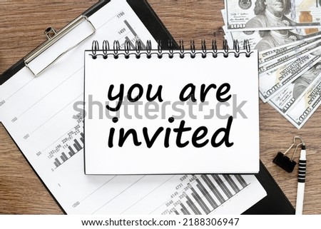 You're Invited Concepts - text on paper on a folder with a clip. wooden table
