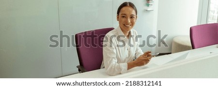 Smiling asian business woman sitting in meeting room and holding phone. High quality photo