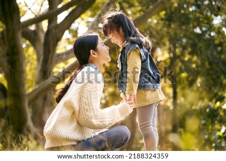 young asian mother and preschool daughter enjoying nature having a good time outdoors in park