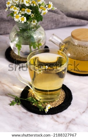 Chamomile tea. Herbal tea. Glass cup with warm fragrant chamomile tea on the background of chamomile flowers, relaxation and detoxification. Phytotherapy. Nutrition science.
