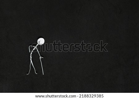 Seniors or old people feeling of isolation, social exclusion and loneliness concept. Elderly man stick figure alone in dark black background creative composition.