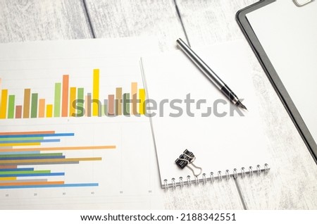 Silver calculator and financial statistics on clipboard pad at office table closeup