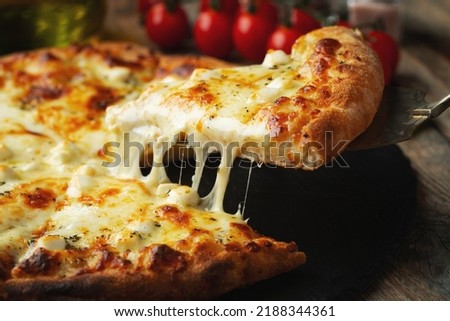 A slice of hot Italian pizza with stretching cheese. Pizza four cheeses with basil on a wooden background. Royalty-Free Stock Photo #2188344361