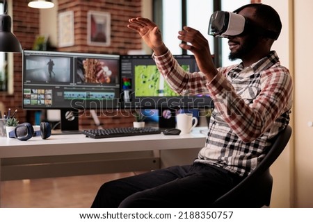 African american filmmaker working with vr glasses, editing video montage on professional post production software. Videographer using augmented reality goggles to edit film footage.