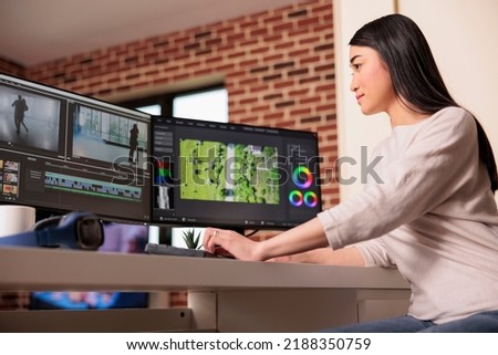 Asian videographer working on editing video and audio footage with professional software to create film content for post production. Using movie montage to edit multimedia movie.
