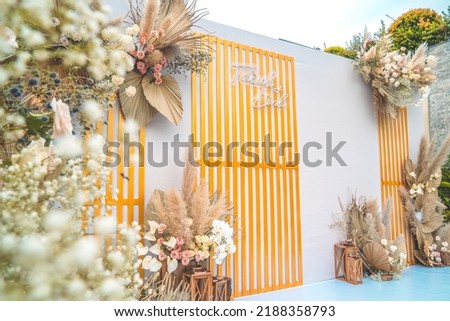 Decorating the arch with flowers and fabric for a wedding ceremony in nature. Wedding Ceremony with flowers outside in the garden with hanging lights.
