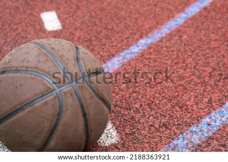 Close-up basketball ball on the red court. Basketball on the street or indoor court. Sports gear without people. Template, sport background	