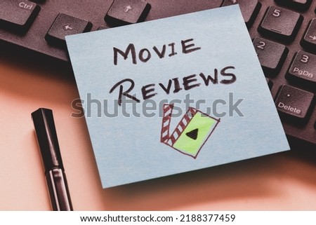 Sticky note with the text Movie Reviews and it's related icon on keyboard. Close up view, selective focus.  Royalty-Free Stock Photo #2188377459