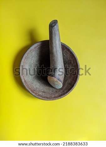 Mortar and pestle isolated on yellow background. Wooden mortar and pestle (Cobek and Ulekan) is an Indonesian Kitchen utensil for making Sambal or spicy sauce.