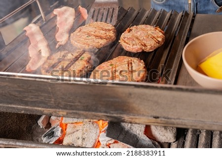 Top view of a raw of hamburgers and meat cooked on a grill