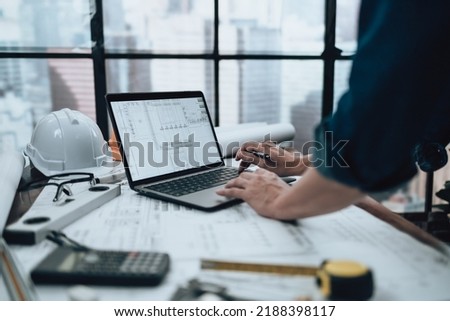 Engineering working with drawings inspection on laptop  in the office and Calculator, triangle ruler, safety glasses, compass on Blueprint. Engineer, Architect, Industry and factory concept. Royalty-Free Stock Photo #2188398117