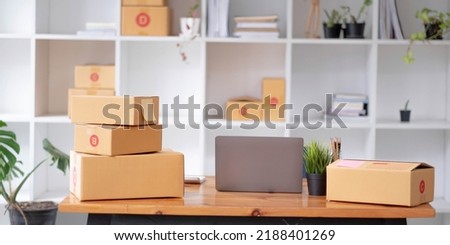 Parcel boxes on shelf and color shopping bags placing near laptop on table. SME business on shopping online at home office packaging on background is popular business.
