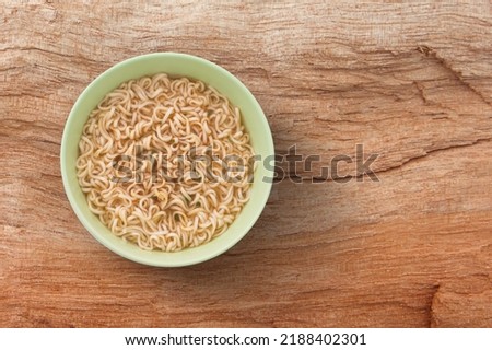 Yellow noodles in green bowl on wooden board background , top view , flat lay.