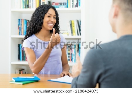 Successful latin american female student learning with teacher on private lessons at desk at classroom Royalty-Free Stock Photo #2188424073