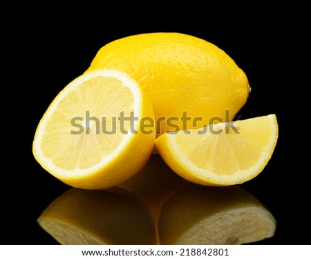 Studio shot of sliced and whole lemons isolated on black background