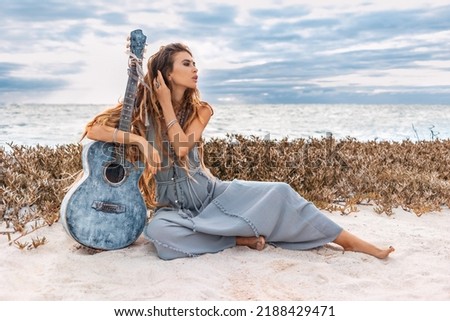 beautiful young stylish woman outdoors at sunset with guitar
