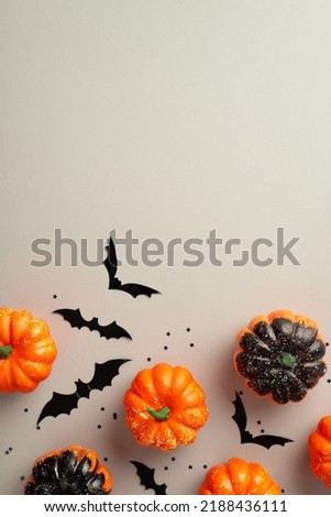 Halloween concept. Top view vertical photo of pumpkins bat silhouettes and confetti on isolated grey background with empty space
