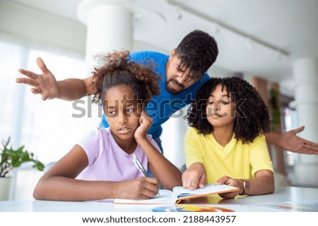 Parents yelling at their daughter while doing her homework at home. Young father and mother helping daughter study at living room. Royalty-Free Stock Photo #2188443957