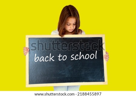 Young girl teenager isolated on colored background. Preparation for school concept. Girl kid gets ready for school. Schoolgirl holding blackboard. Back to school concept. Free copy space.