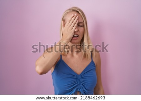 Young caucasian woman standing over pink background yawning tired covering half face, eye and mouth with hand. face hurts in pain. 