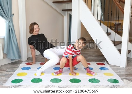 Twister game. Happy family having fun together, playing twister game at home. Mother and child, kid, boy plays in twister. Active rest, recreation, indoor game. Child with parent plays twister game Royalty-Free Stock Photo #2188475669