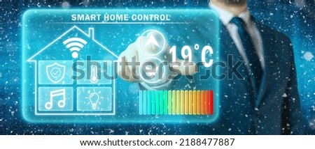 Man adjusting heating temperature on a virtual screen of smart home controller, winter blizzard background. Concept of forced thrift because increased price for heating home.