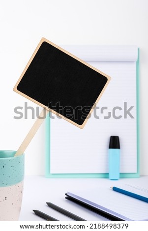Small Blackboard With Important Message In Cup On Desk With Clipboard, Notebooks And Marker. Little Board With Crutial Information On Table With Paper. Current Ideas Presented