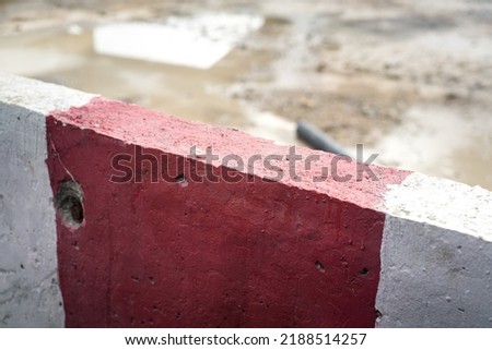 Close-up at concrete road block with red-white pattern, using to barricade the road construction area. Industrial and transportation object photo.