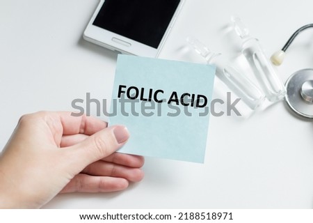 Folic Acid written on a card in doctors hand