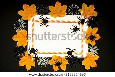 Frame for writing the text of the celebration of the holiday Halloween.  On a black background, a white sheet of paper, orange maple leaves, decorative cobwebs and spiders.  Party invitation.