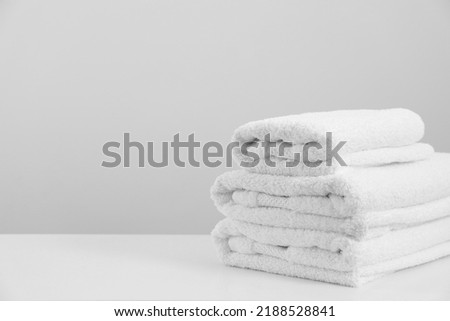 Stack of clean soft white towels on table against light grey background. Space for text Royalty-Free Stock Photo #2188528841