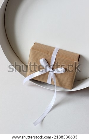 Decorated Holiday Gift. Wrapped in Brown Kraft Paper Present Decorated with White Ribbon Bow. Christmas, New Year Mockup with Copy Space.