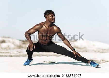 Good stretch. Handsome african american man in sportswear warming up outdoors. Black Man stretches his hamstrings. Photo of an athletic man