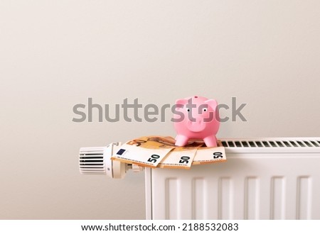 Save heating costs, piggy bank and Euro money bank notes on radiator, beige background