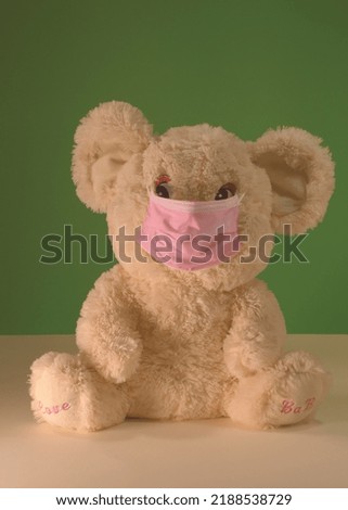 A bear toy wears a pink medical mask properly on his face. Pink and greeen colors.Common mask-wearing mistakes. Education image for preschool classroom.
