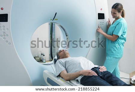 Young female doctor examining man in 40s with CT scanner. Computerised tomography. Royalty-Free Stock Photo #218855224