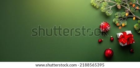 Merry Christmas and Happy Holidays greeting card, frame, banner. New Year. Noel. Christmas gifts red ribbons, ornaments on green background top view. Winter holiday xmas theme. Flat lay. Royalty-Free Stock Photo #2188565395