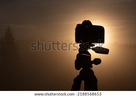 PHOTO CAMERA ON THE TRIPOD WITH LANDSCAPE VIEW AT THE SUN RISE, BEAUTY OF NATURE, PHOTOGRAPHY BACKGROUND