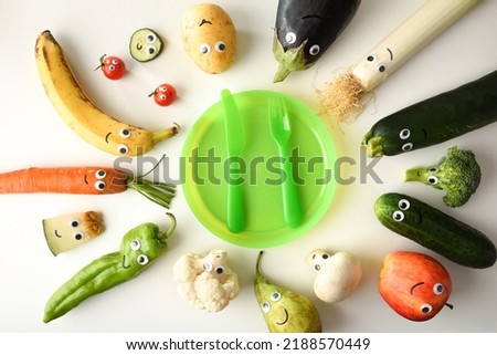 Backgound with attractive plate of funny fruits and vegetables served for child with red children's cutlery on white table. Top view. Royalty-Free Stock Photo #2188570449