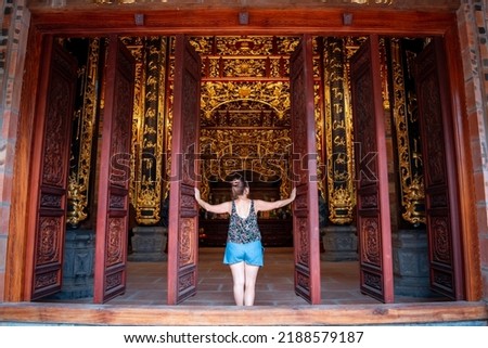 Young tourist at the gates of a temple in Vietnam. Young woman opening temple doors. Tourist at the Vietnamese temple gates