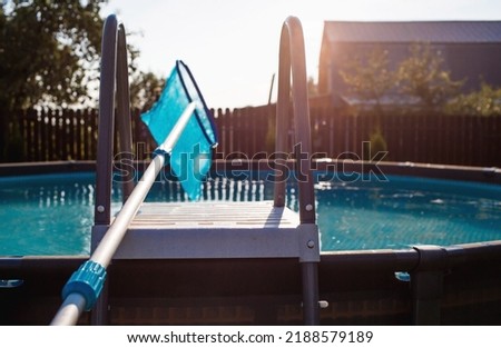 Abstract blur and defocused background. Cleaning of a swimming pool with a metal frame with a mesh from dirt. Pool cleaner during operation. Solar banner.The concept of summer holidays.