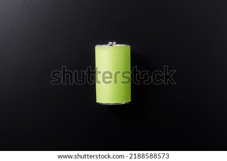 energy, power and sustainability concept - close up of alkaline battery on black background