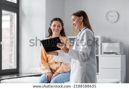 medicine, healthcare and people concept - female doctor with tablet pc computer talking to smiling woman patient at hospital Royalty-Free Stock Photo #2188588635