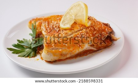 Fresh backed tilapia fillet on white plate with lemon and herbs Royalty-Free Stock Photo #2188598331