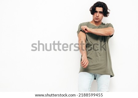 Portrait of handsome confident  stylish hipster lambersexual model.Sexy man dressed in over size T-shirt and jeans. Fashion male isolated in studio. Posing near white wall Royalty-Free Stock Photo #2188599455